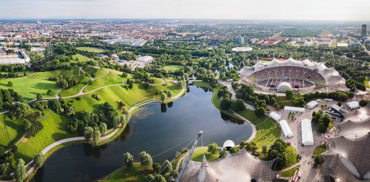 Panorámica desde el aire del estadio olímpico al lado de un lago y al fondo la ciudad