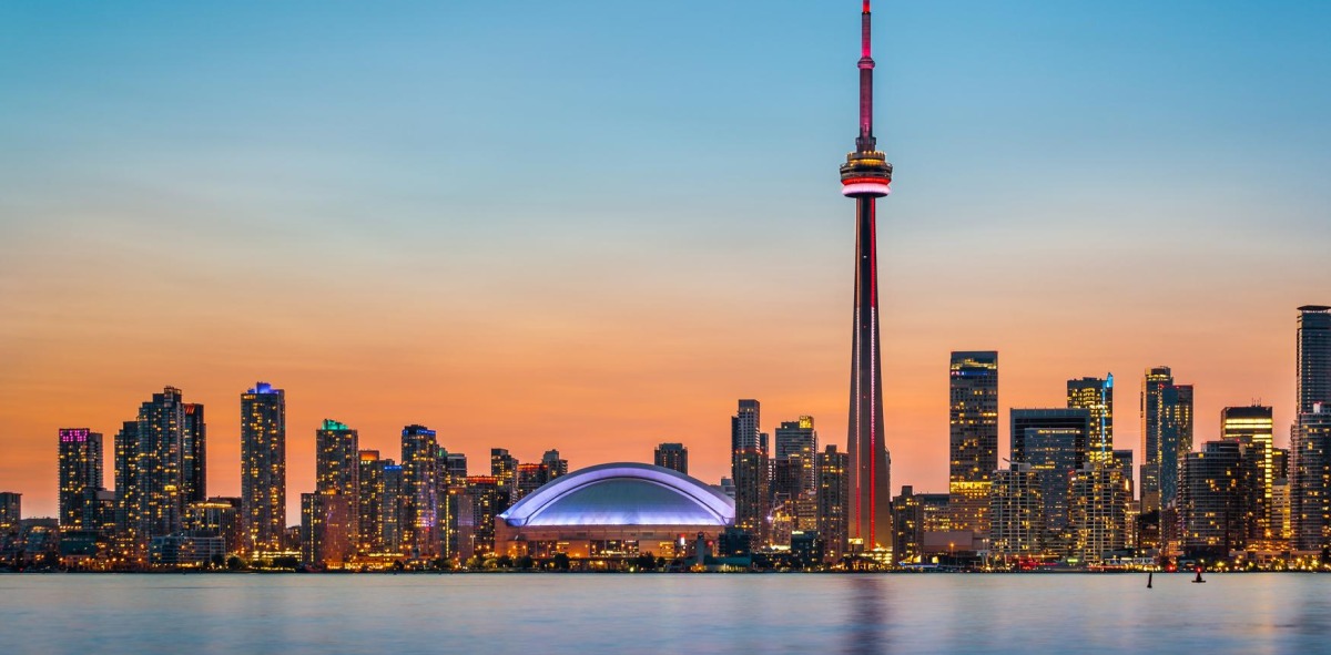 Skyline desde el mar de Toronto al atardecer con los edificios iluminados, donde sobre sale la altura de la Torre CN