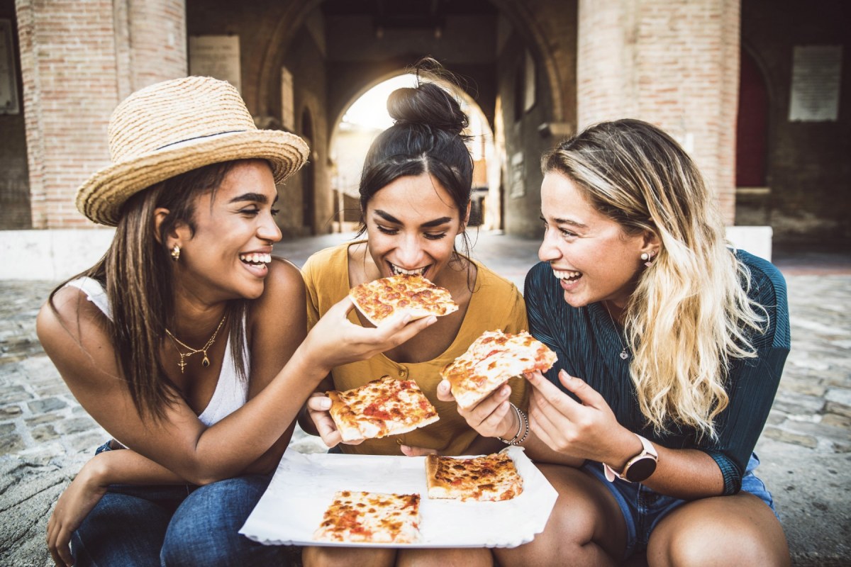 tres jovenes amigas comiendo pizza italiana