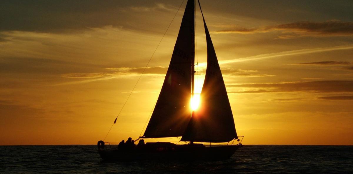 Velero navegando al atardecer a toda vela