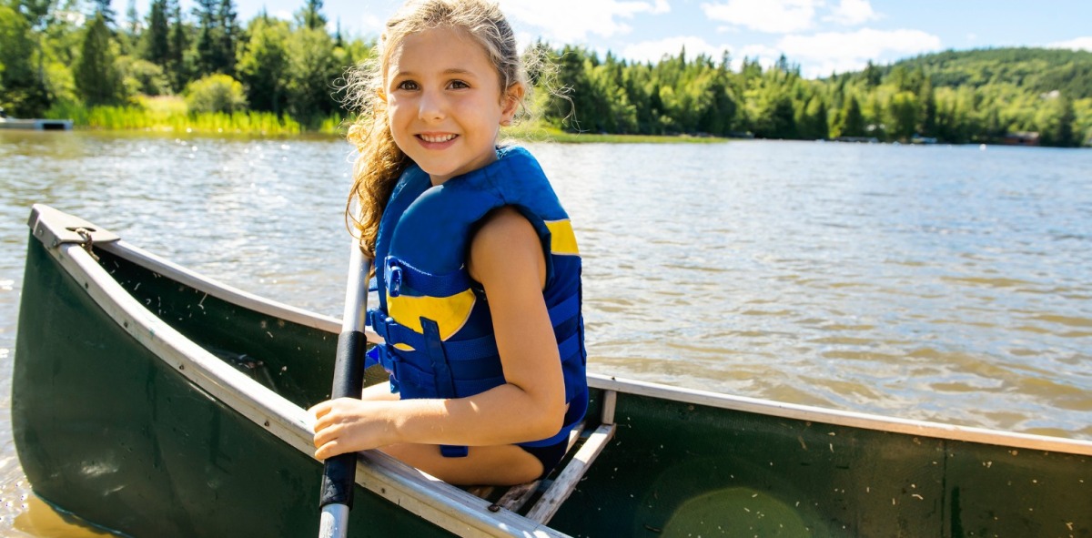Niña posando en una canoa con un remo en el pantano
