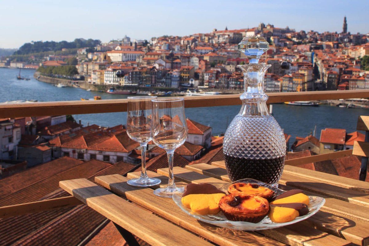 Vista desde una terraza de la ciudad, en la mesa dos copas de vino Oporto y plato con pasteles típicos