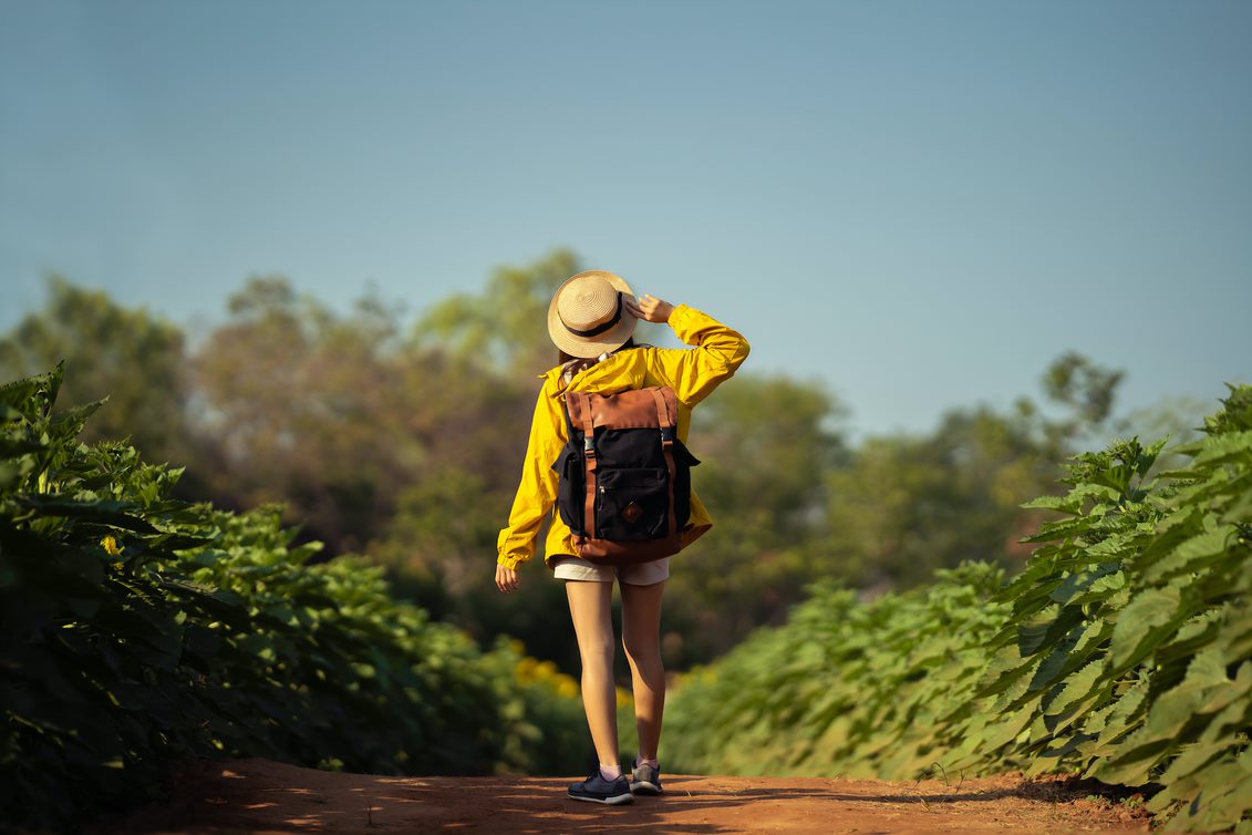 Chica de espaldas con mochila por un sendero de tierra