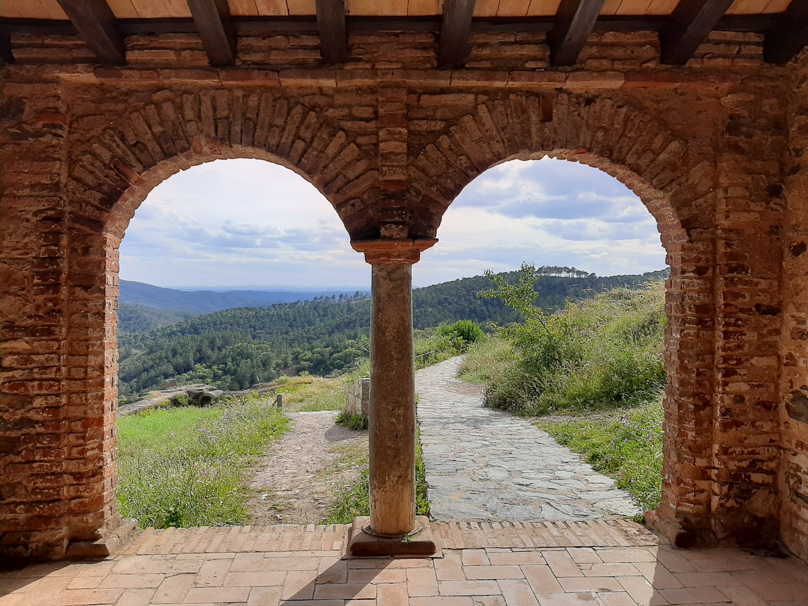 Panorámica de montes verdes y unos arcos de piedras como un camino