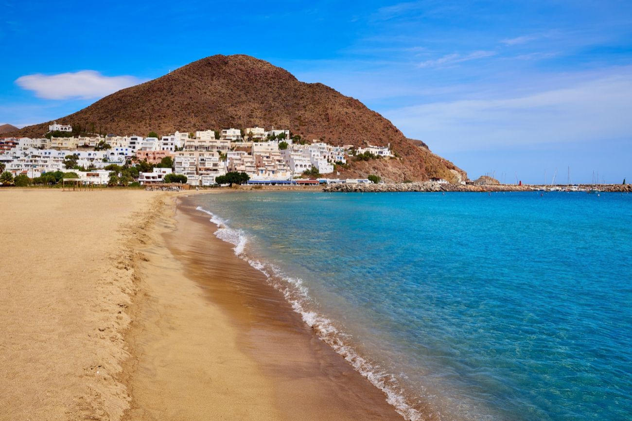 Pueblo con casas de color blanco en la ladera de una montaña y junto a la playa