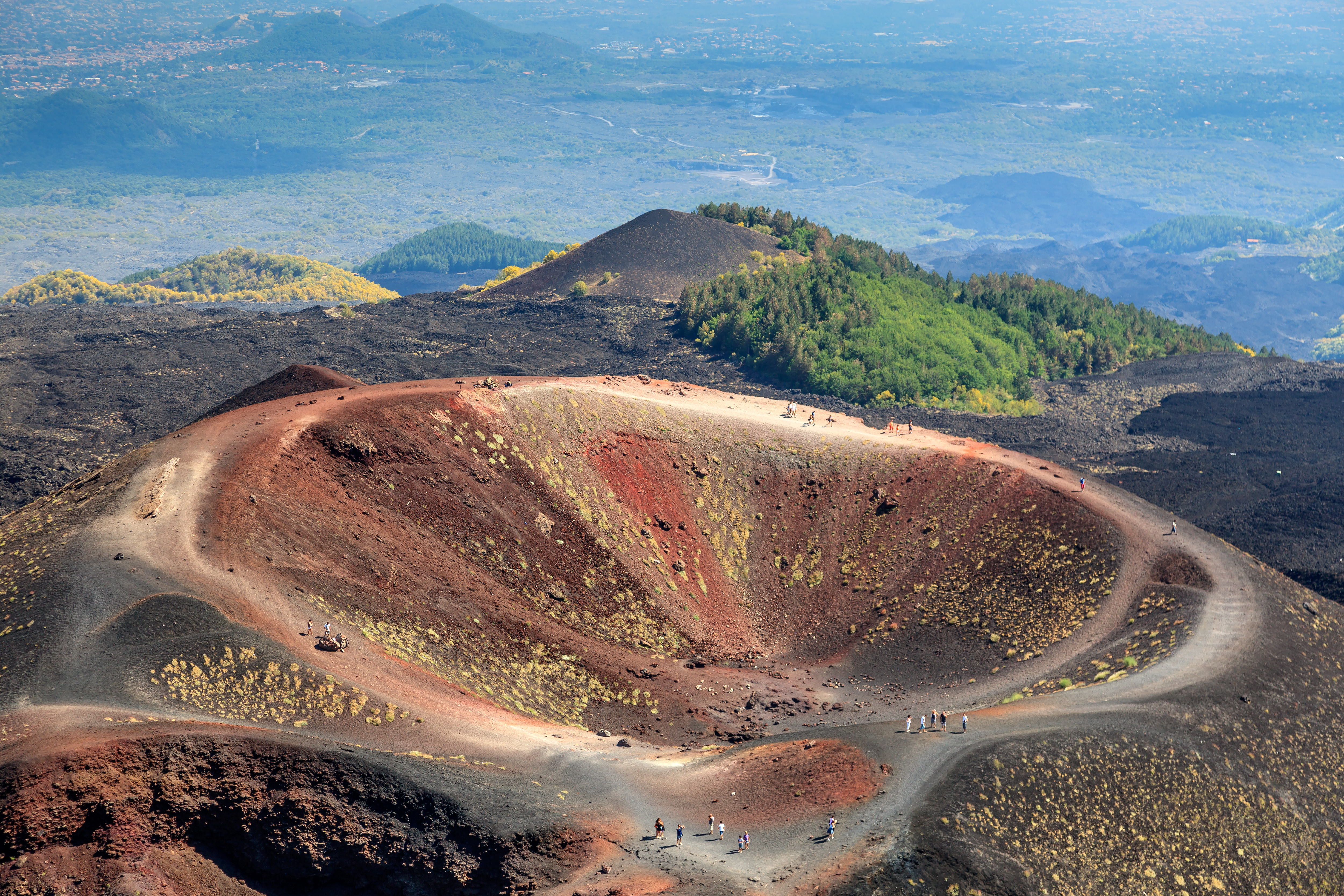 foto desde el cielo de la boca de un volcán y gente paseando por los caminos