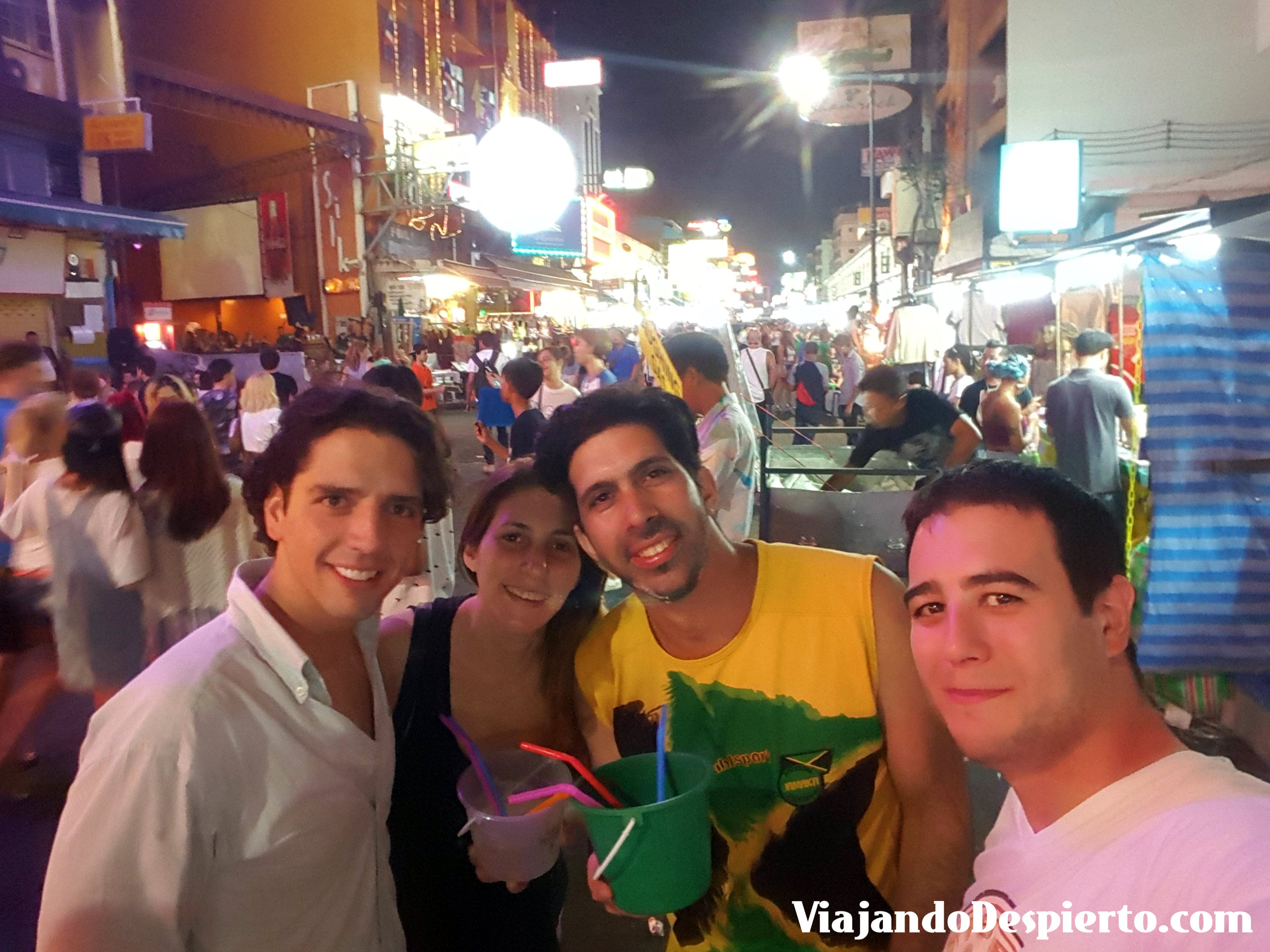 Tres chicos y una chica posando en una calle muy concurrida por la noche
