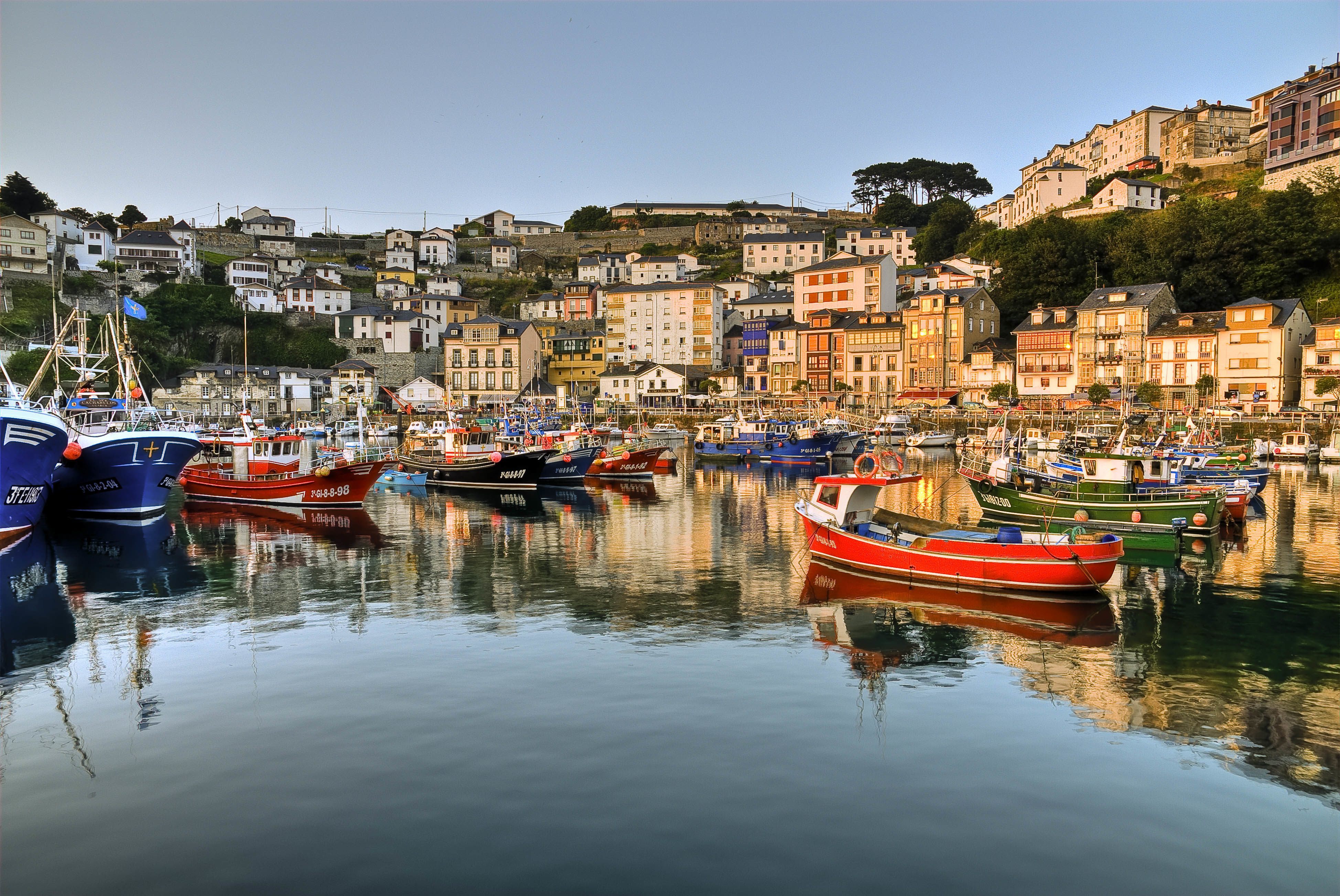 Puerto pesquero lleno de barcas de pesca y en la ladera de la montaña un pueblo escalonado