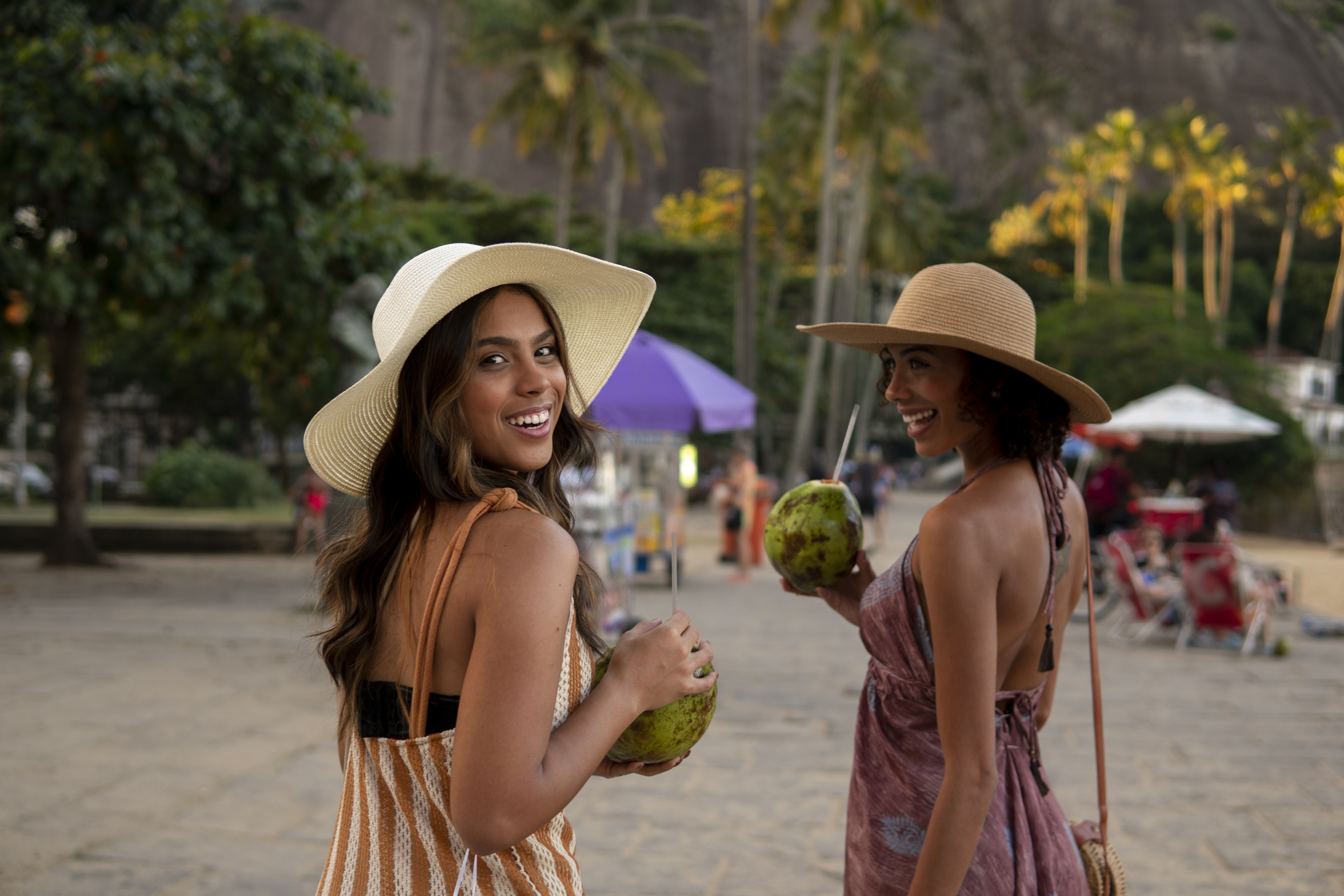 Amigas singles en la playa tomando agua de coco