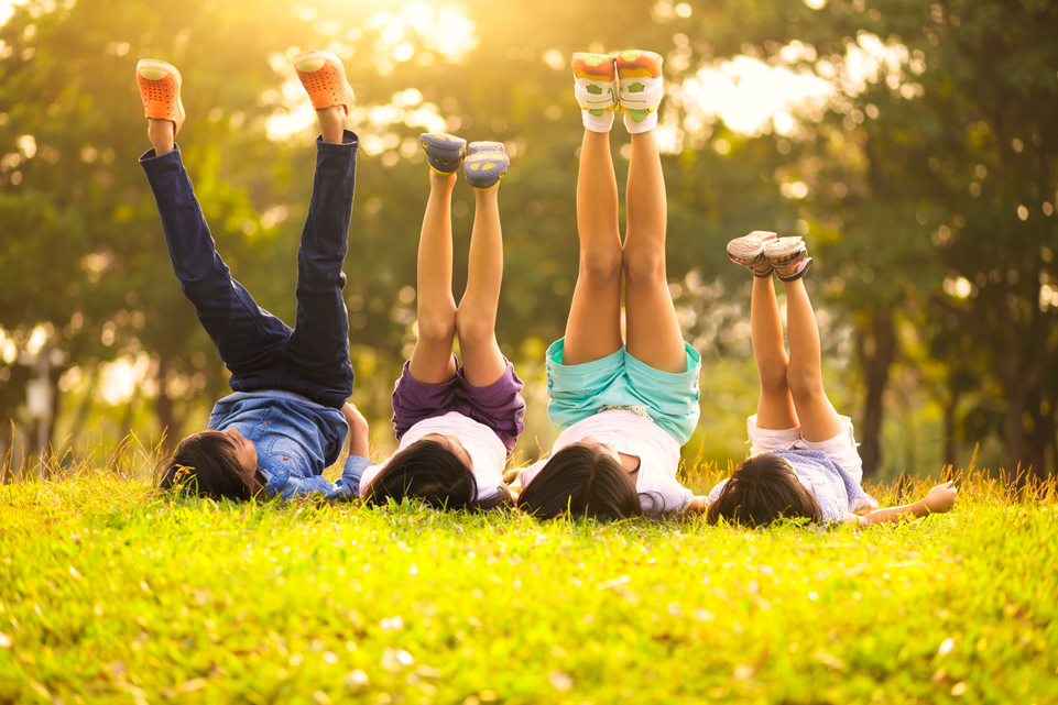 Niños tumbados en el cesped con las piernas subidas