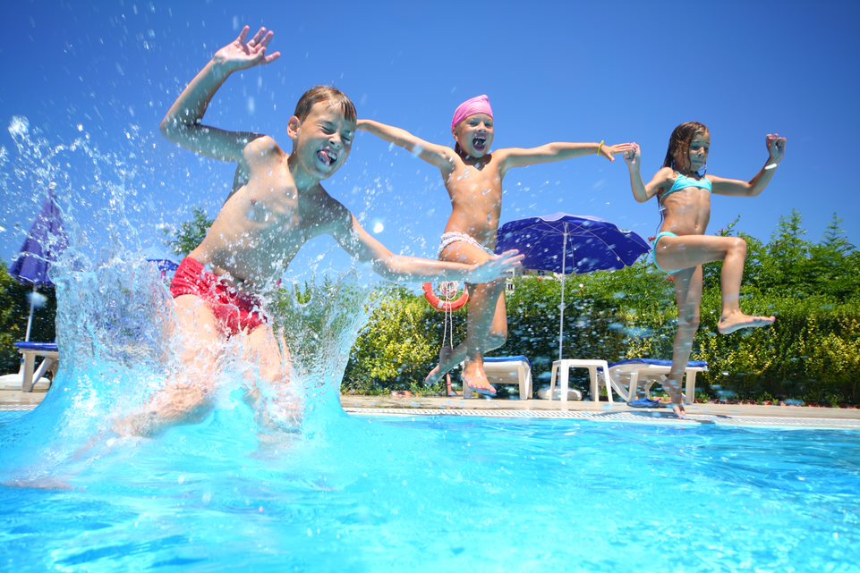 Tres niños en bañador tarándose a la piscina