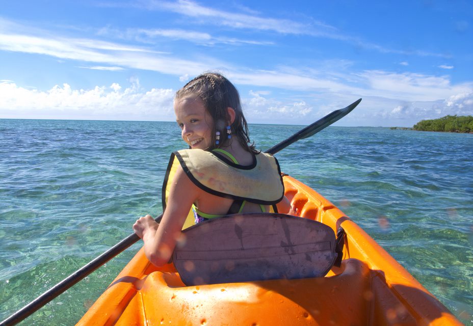 Niña montada en un kayax sonriendo en el mar