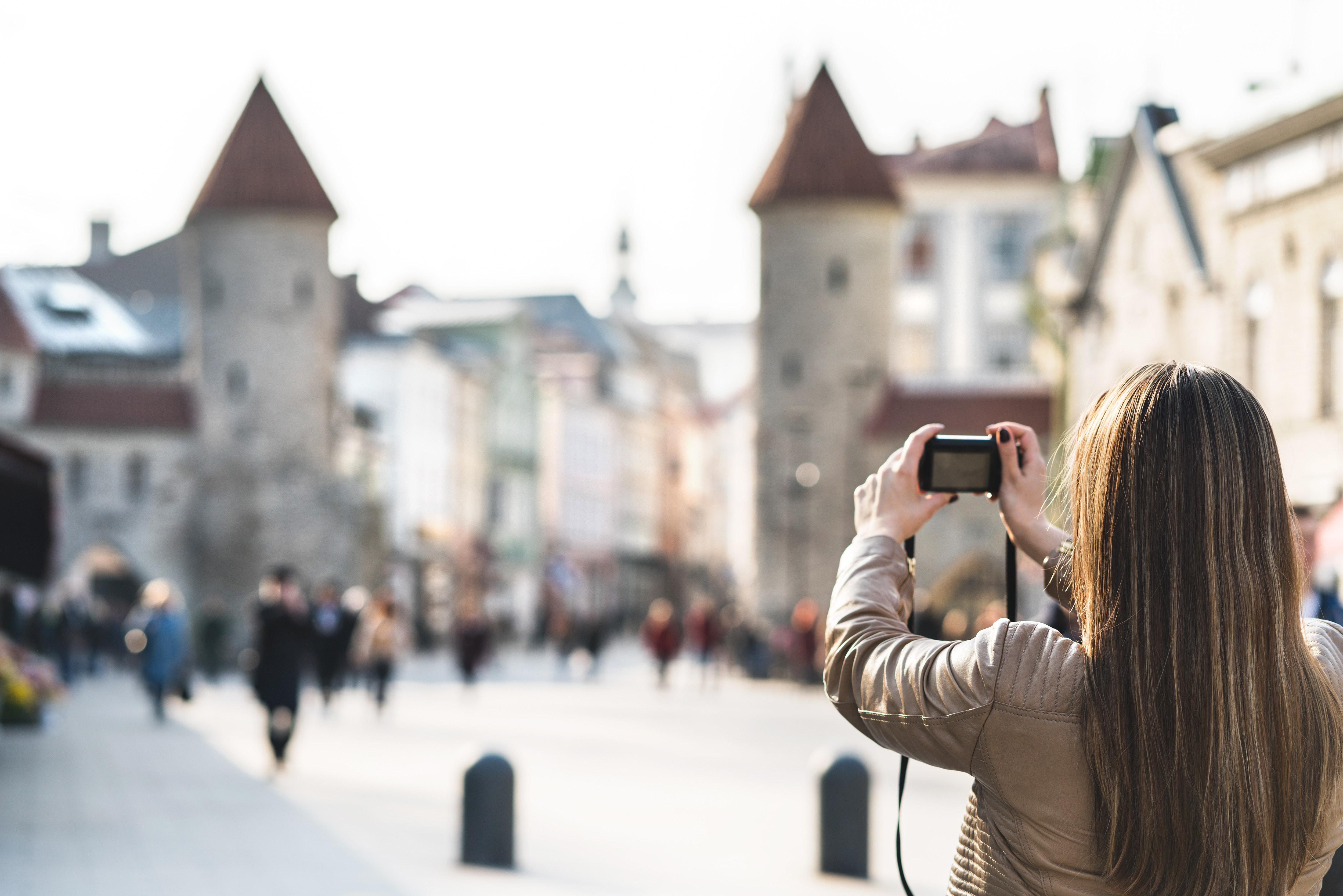 Mujer de espaldas haciendo foto a unas torres antiguas en una plaza