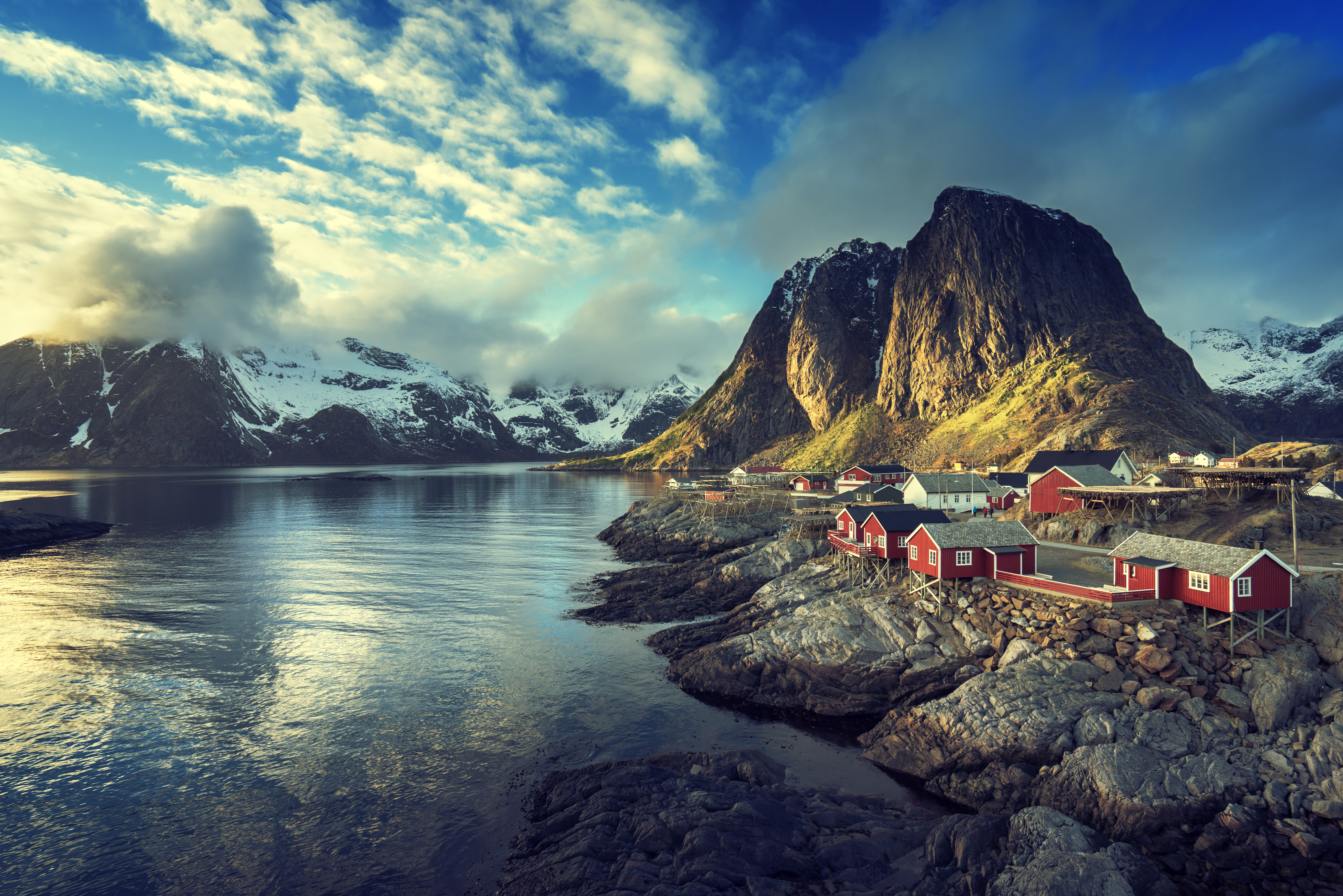 Reine, pueblo de las Islas Lofoten en Noruega. La imagen muestra sus icónicas casas rojas de pescadores alineadas en la costa rocosa junto a un fiordo