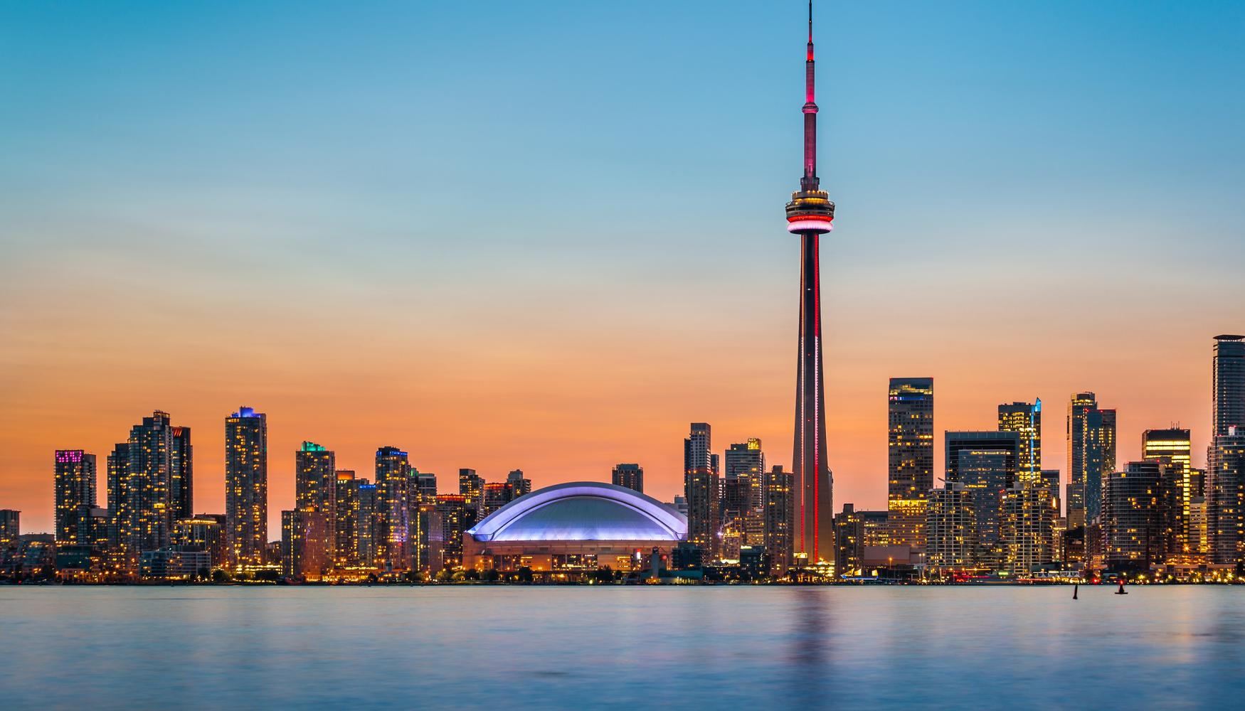 Skyline desde el mar de Toronto al atardecer con los edificios iluminados, donde sobre sale la altura de la Torre CN
