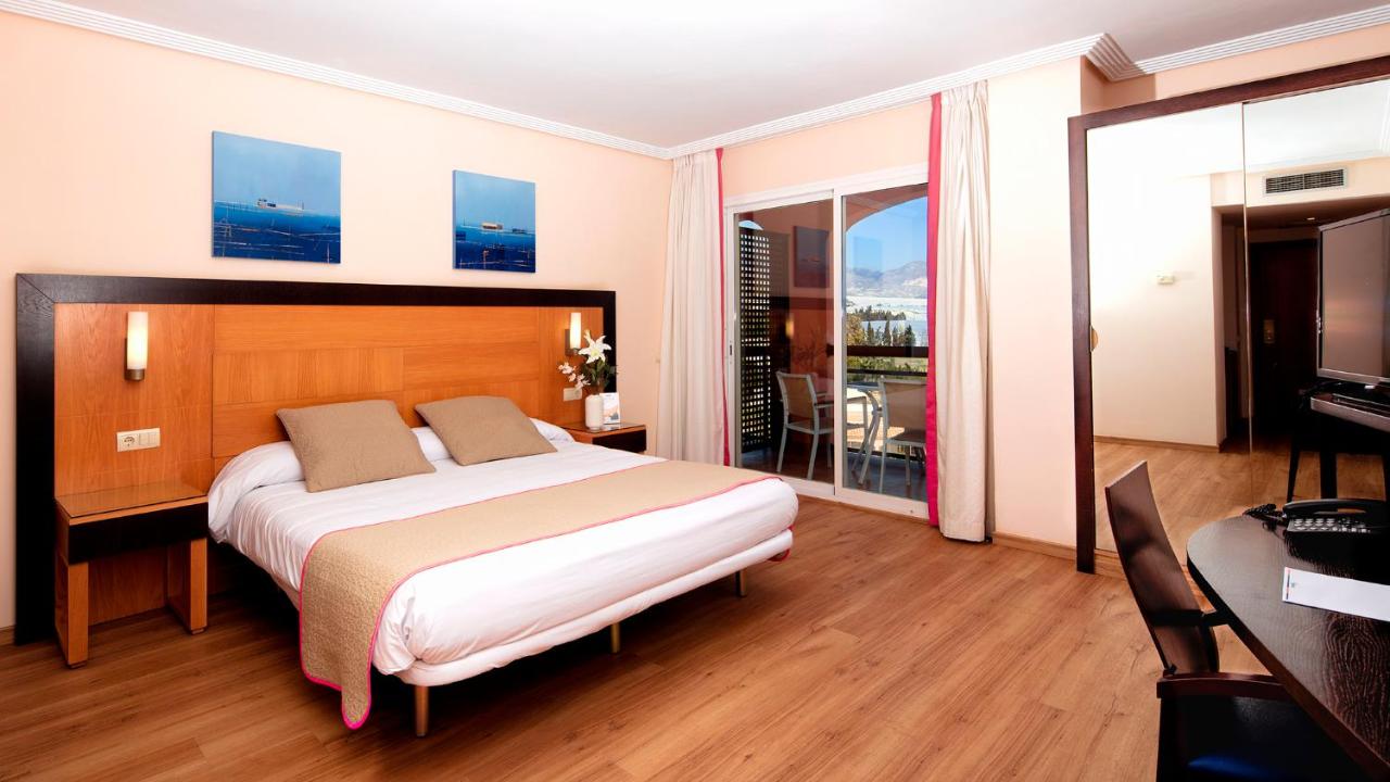 Habitación de un hotel donde aparece una cama grande y una terraza
