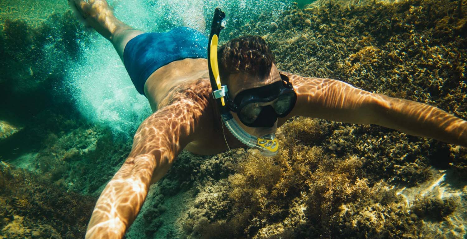 Joven haciendo snorkel debajo del mar