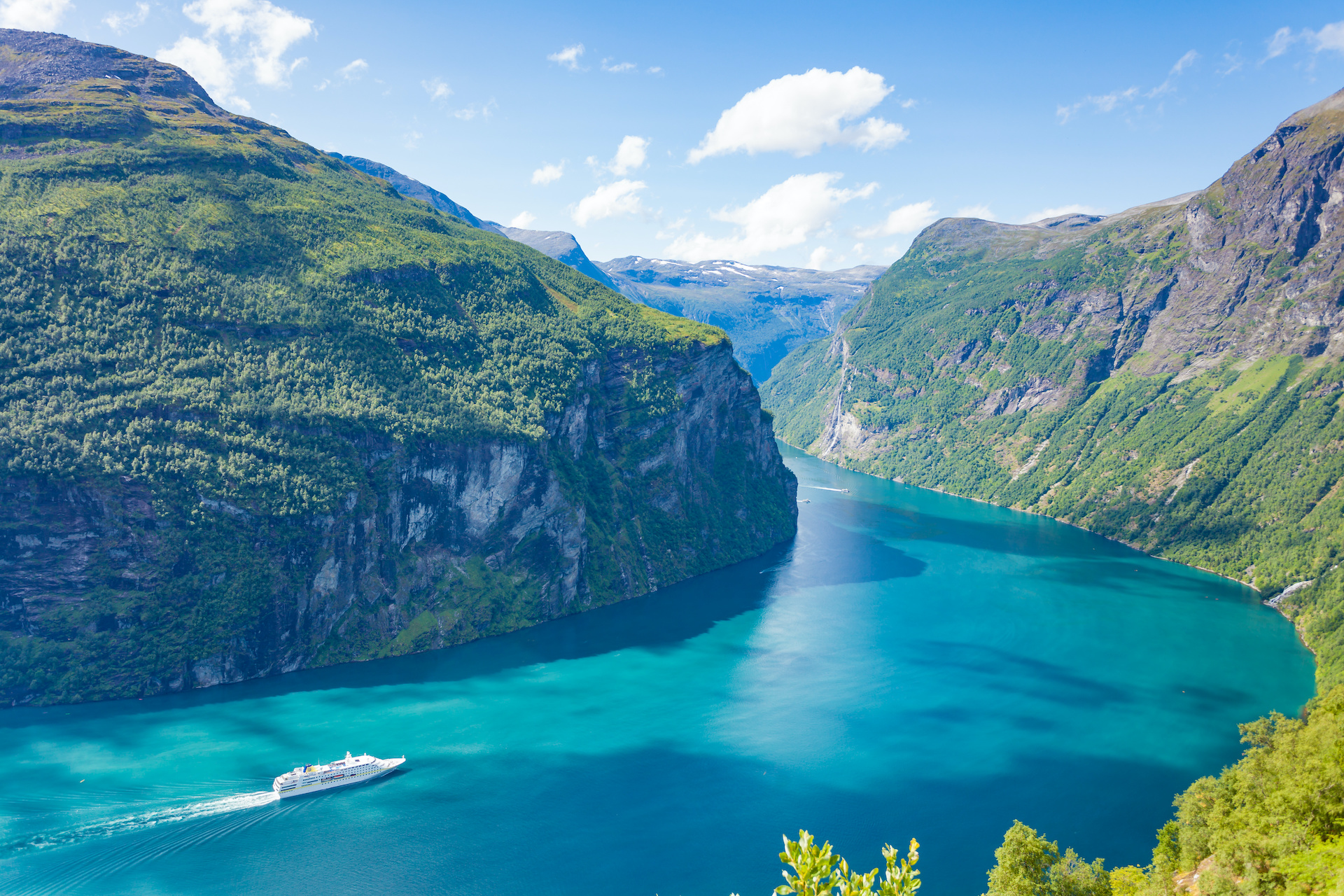 Panorámica desde lo alto de un fiordo donde se aprecia un crucero navegando por las aguas del fiordo