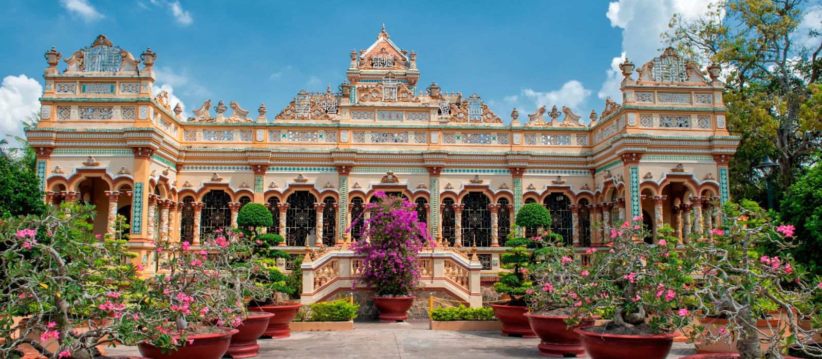 Vistas de un palacio de colores rodeado de plantas de colores rosas