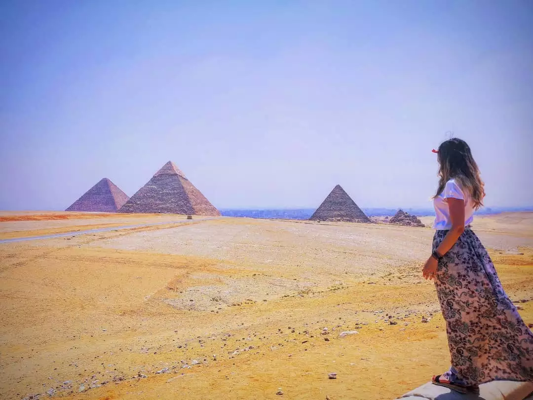 Mujer de espaldas contemplando al fondo las pirámides de Giza