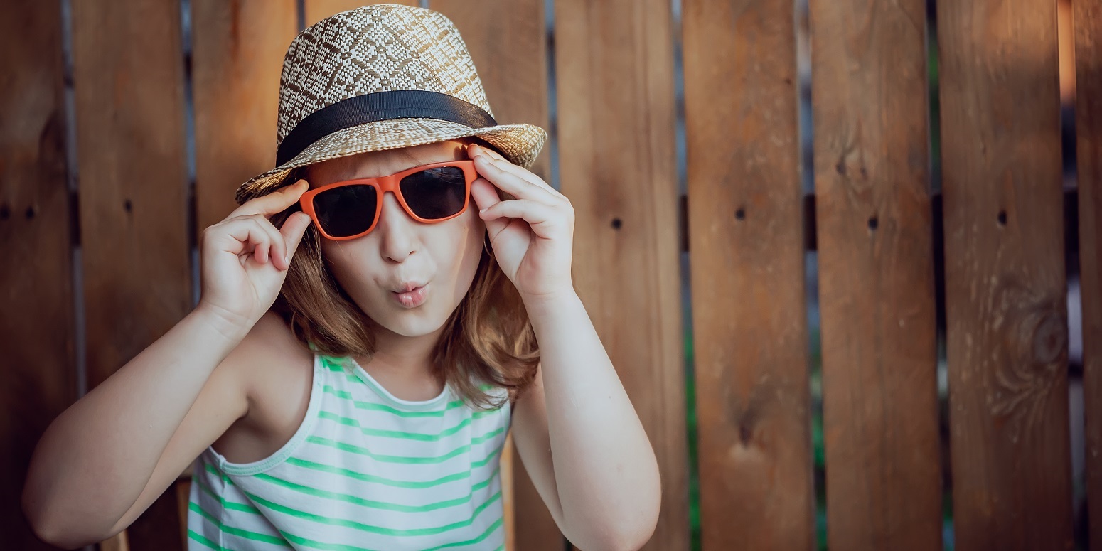 Niña posando con gafas de sol y sombrero