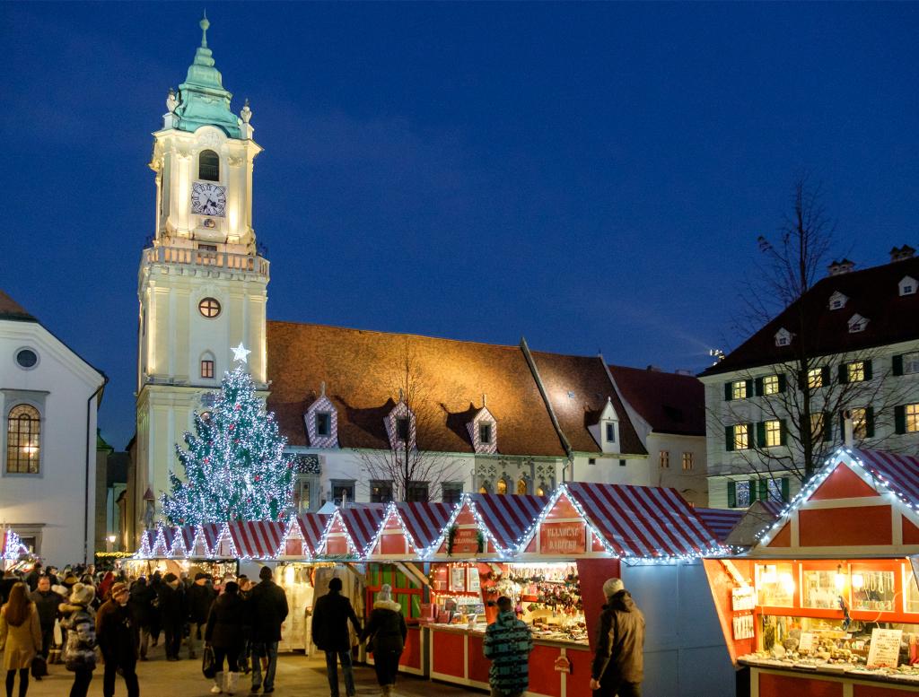 Plaza de un mercadillo con una iglesia y las casitas decoradas con luces navideñas