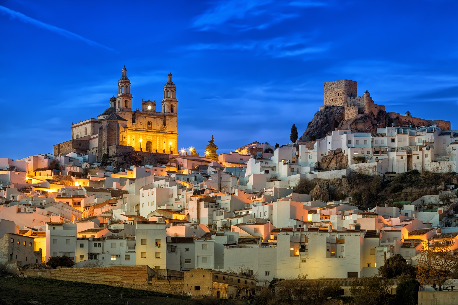 Pueblo en la montaña de casas blancas y a lo alto una iglesia y un castillo