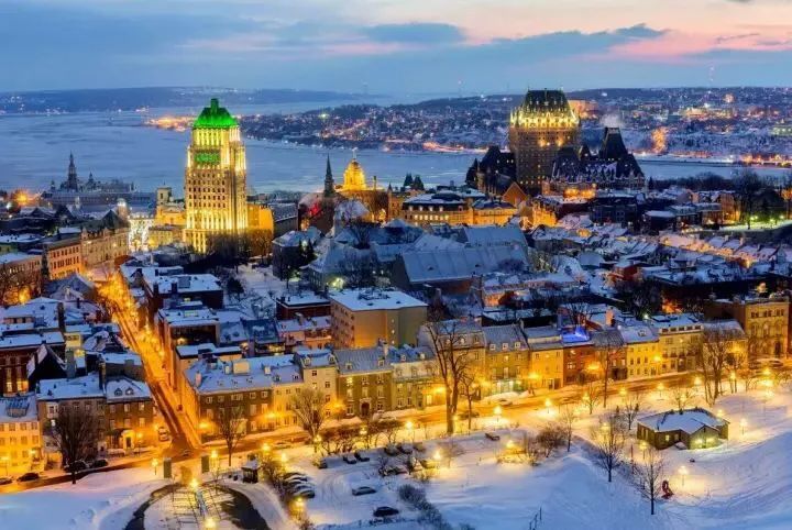 Panorámica de Quebec de noche y nevada, con los edificios iluminados, al fondo el rio donde esta situada