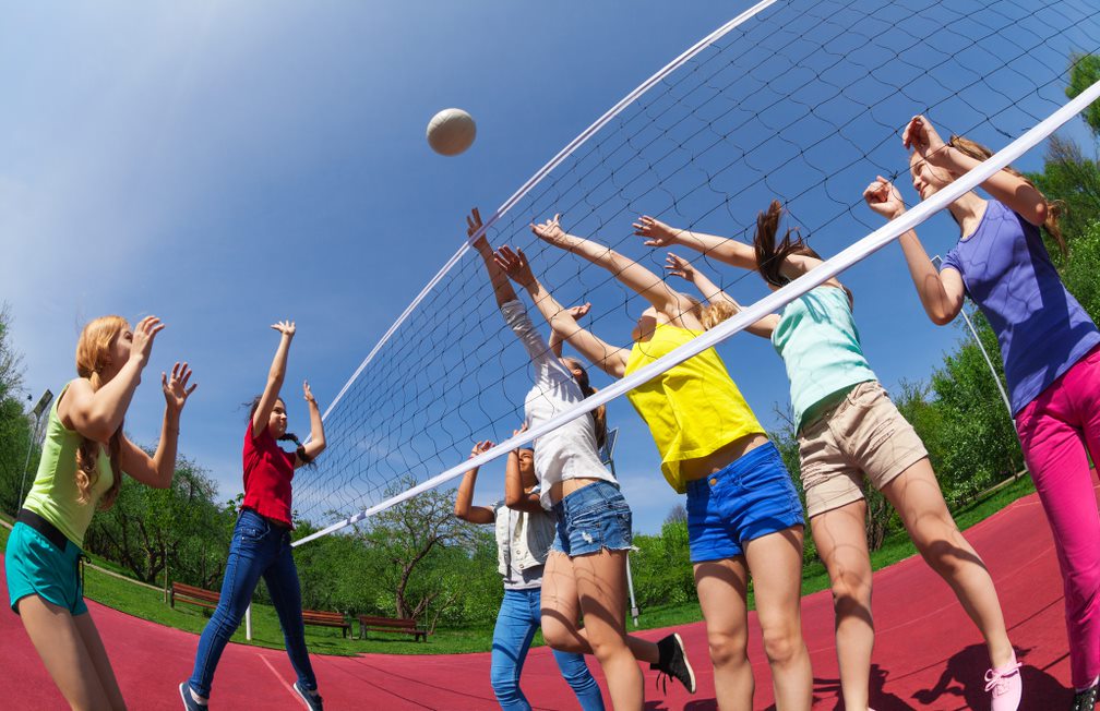 Chicas jugando al Voleibol, al fondo un parque